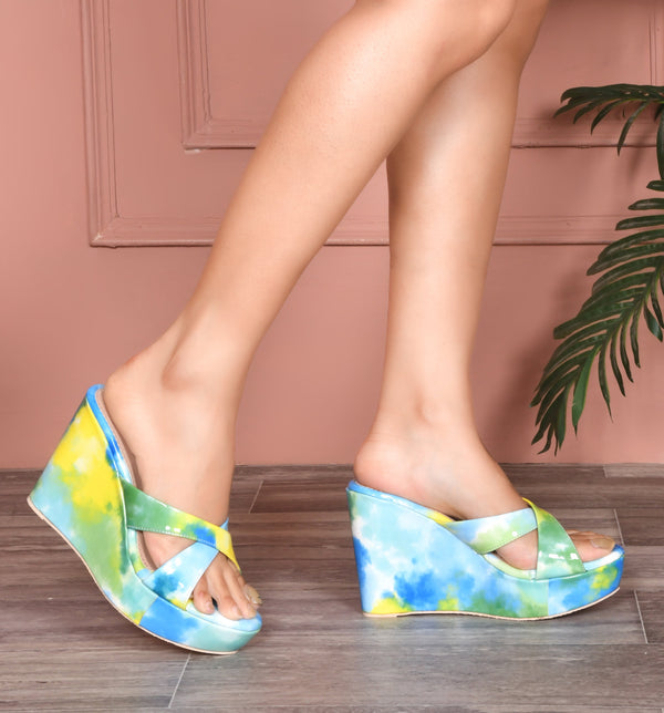 Platform wedge heels in blue yellow watercolor print with criss cross straps, open toe slip-on design.