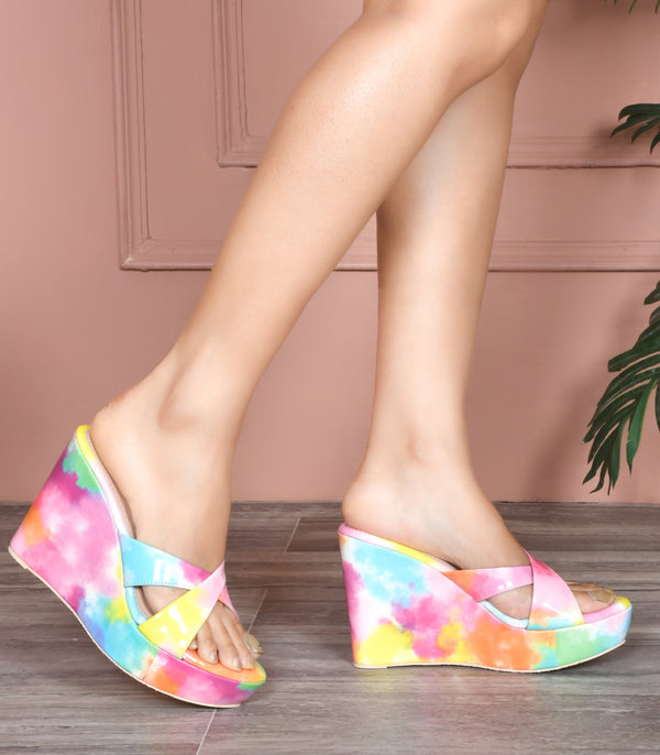 Platform wedge heels in pink watercolor print with criss cross straps, open toe slip-on design.