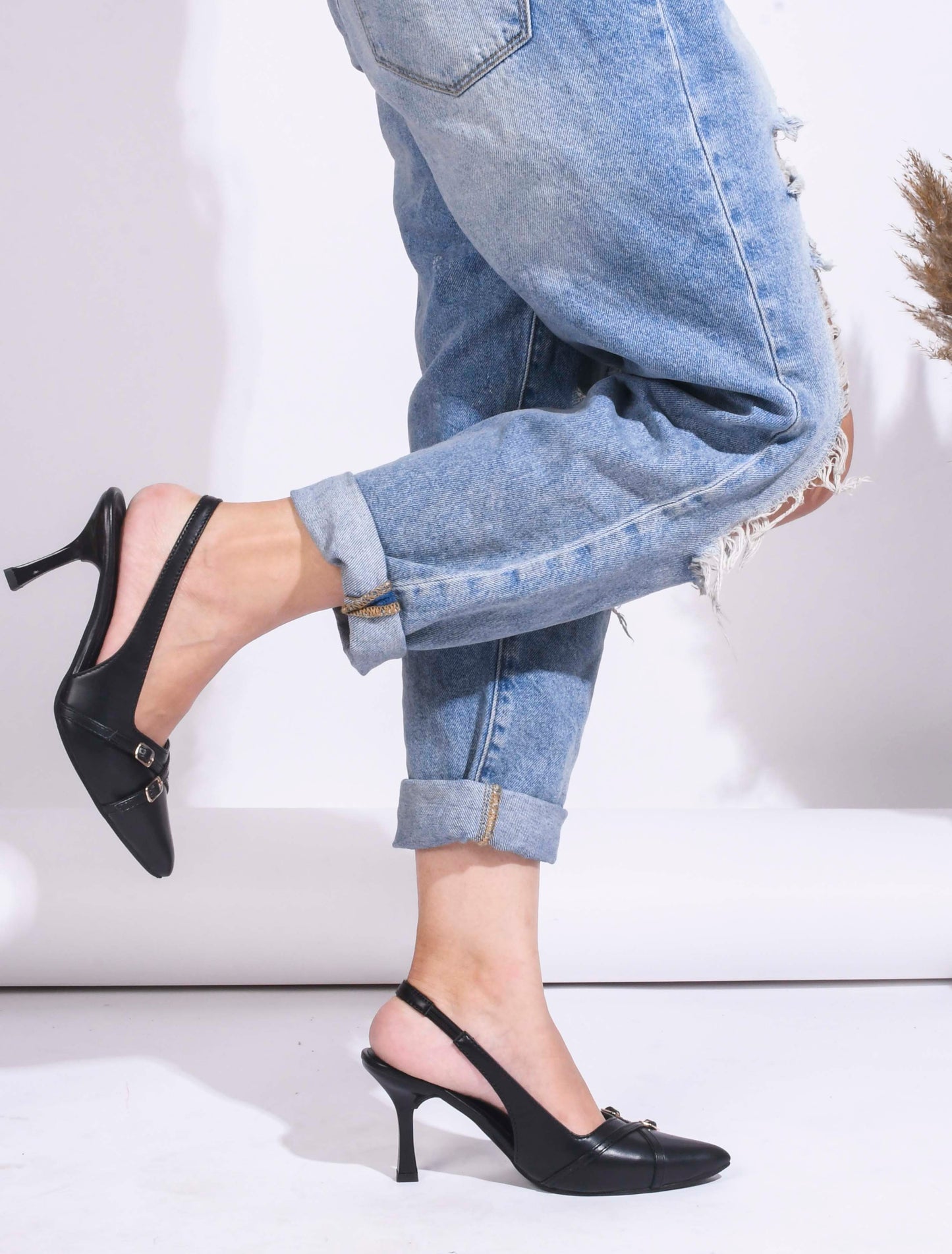 A pointed-toe slingback heel with strap and buckle details on the vamp and an adjustable strap
 Black