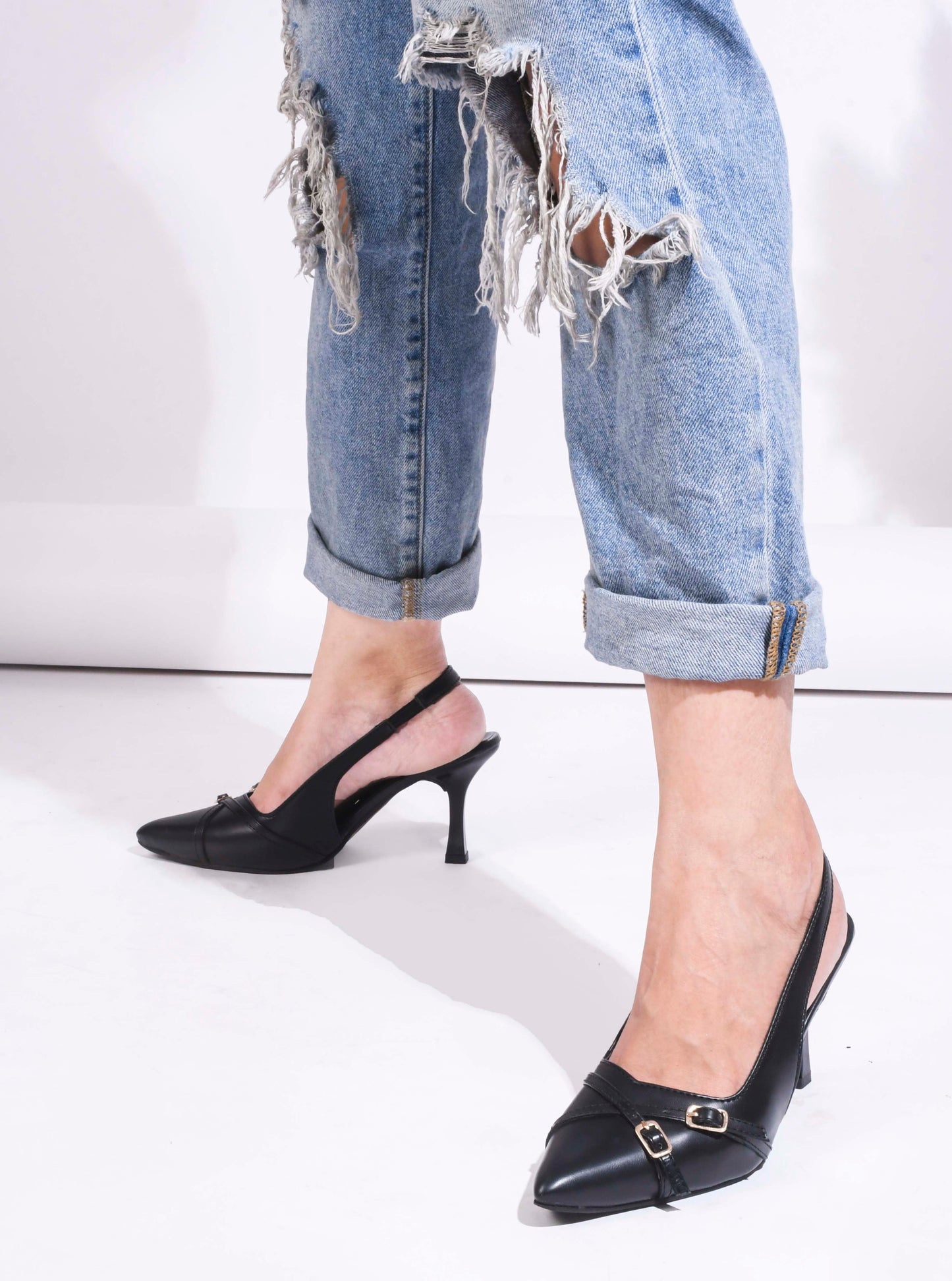 A pointed-toe slingback heel with strap and buckle details on the vamp and an adjustable strap
 Black