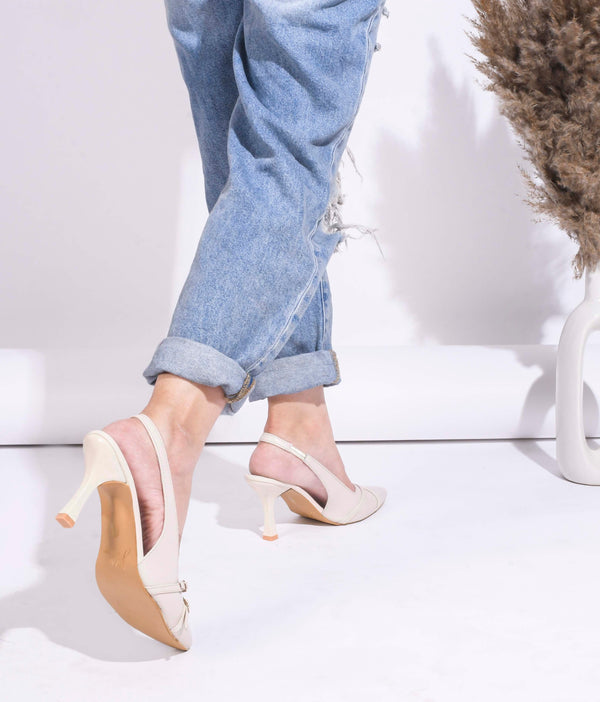 A pointed-toe slingback heel with strap and buckle details on the vamp and an adjustable strap
 Cream
