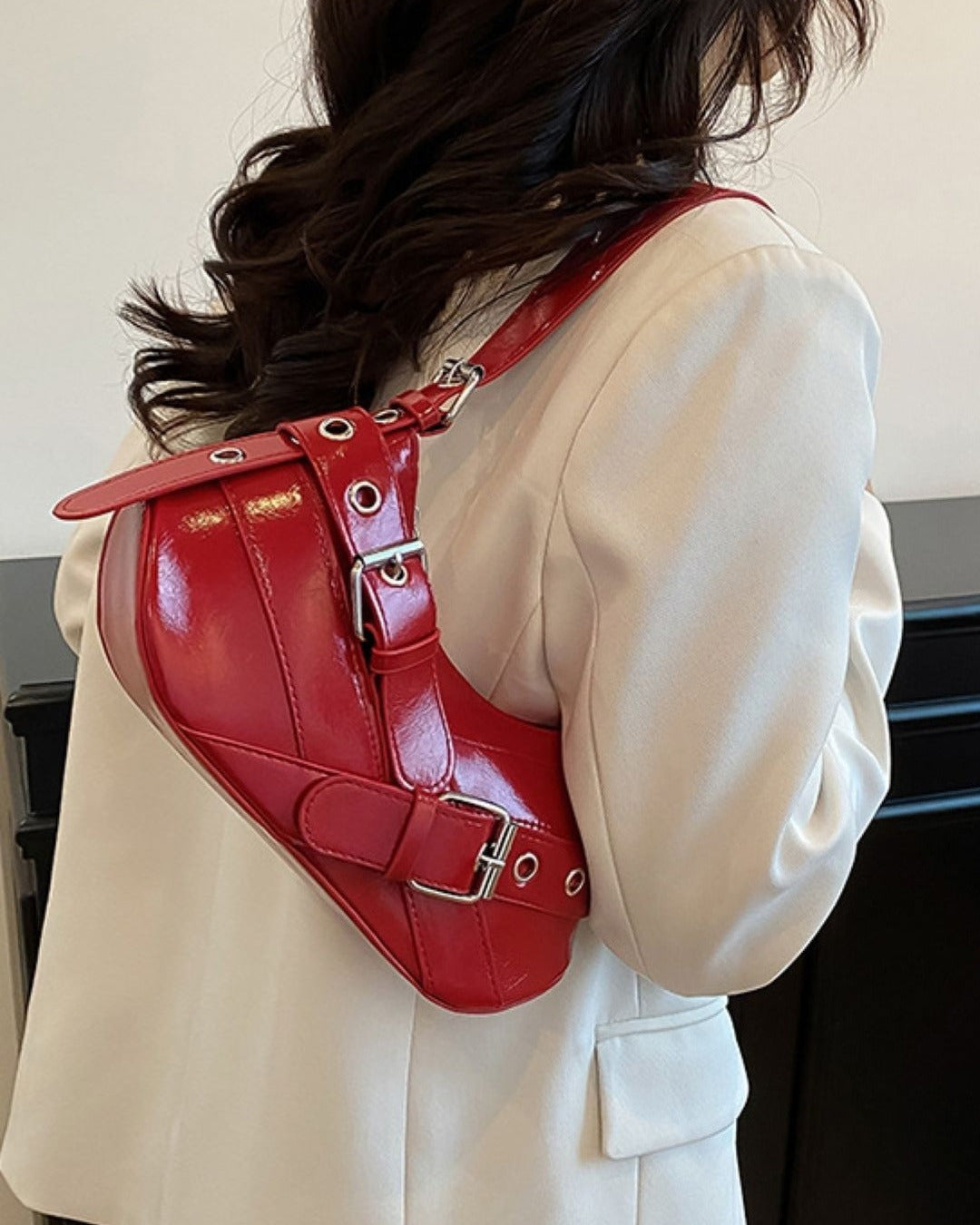 Hobo shoulder bag in red featuring double buckle straps, silver hardware, and an adjustable strap design.