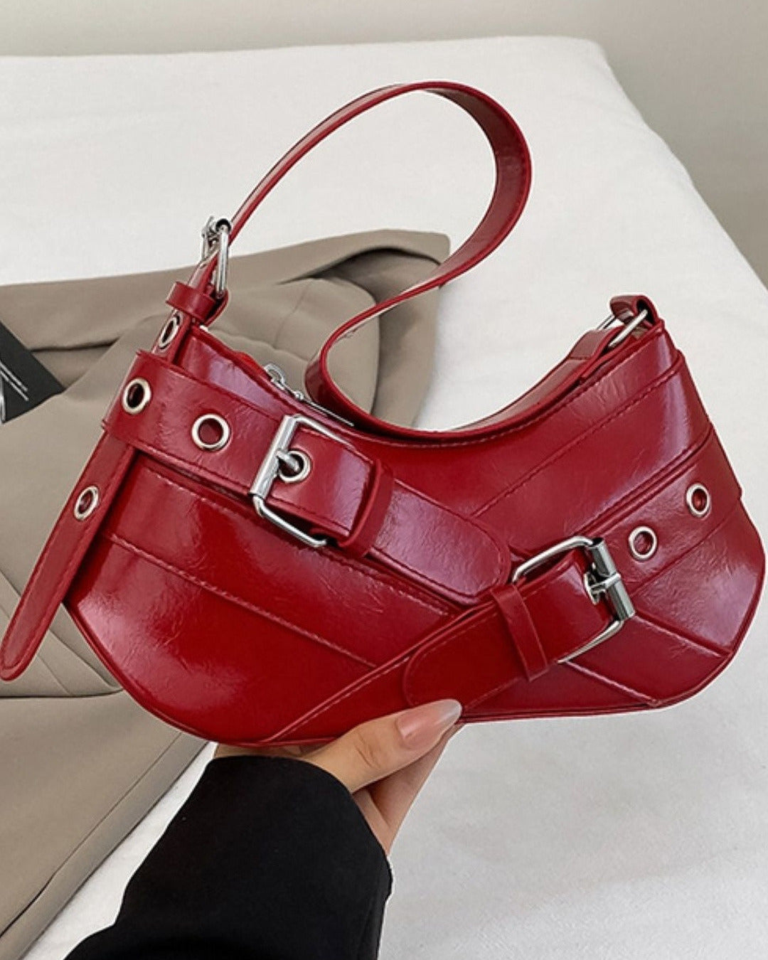 Hobo shoulder bag in red featuring double buckle straps, silver hardware, and an adjustable strap design.