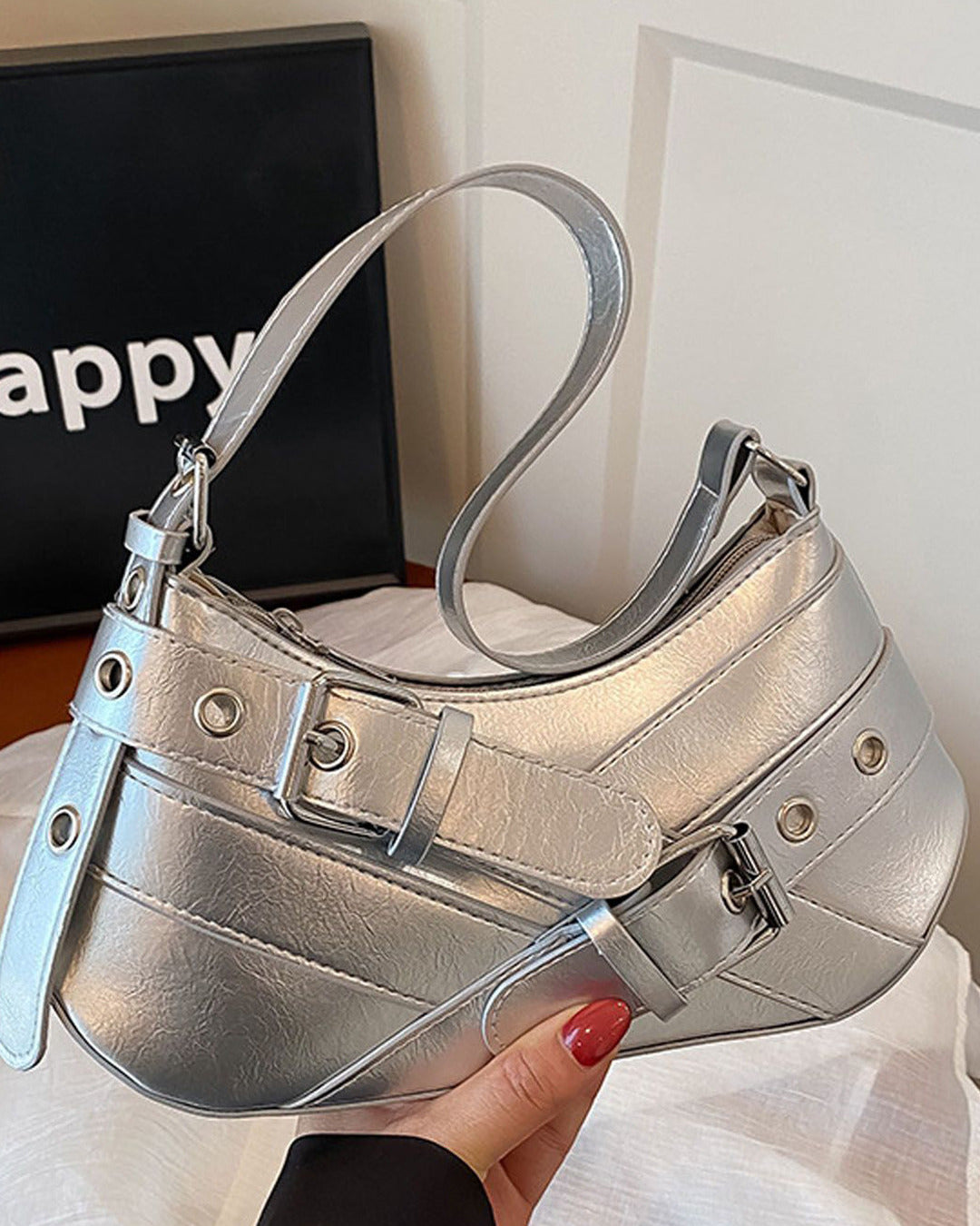 Hobo shoulder bag in silver featuring double buckle straps, silver hardware, and an adjustable strap design.