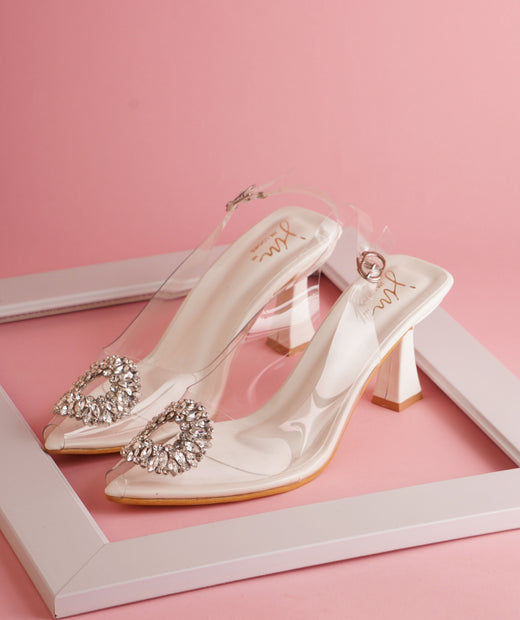 Transparent heels for women with crystal embellished brooch, pointed toe, slingback strap and white kitten heel.
