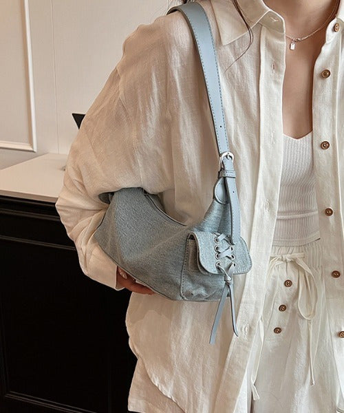 Blue glossy hobo shoulder bag with adjustable strap, side lace-up pockets, and sleek zip closure design