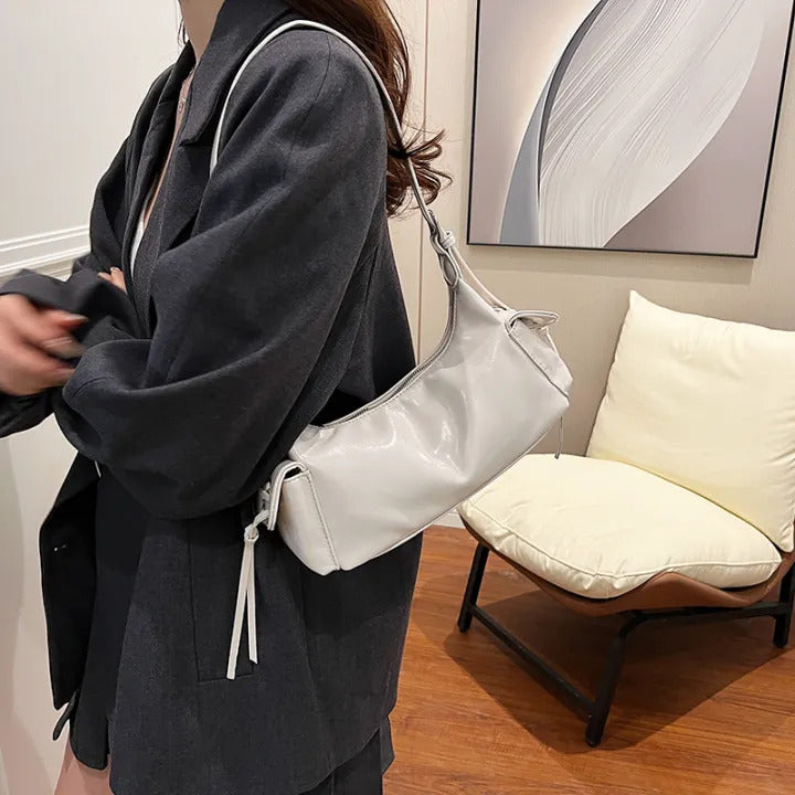White glossy hobo shoulder bag with adjustable strap, side lace-up pockets, and sleek zip closure design