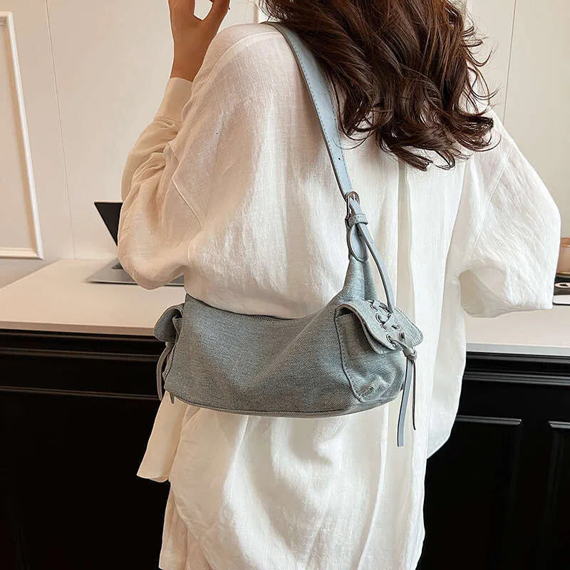 Blue glossy hobo shoulder bag with adjustable strap, side lace-up pockets, and sleek zip closure design