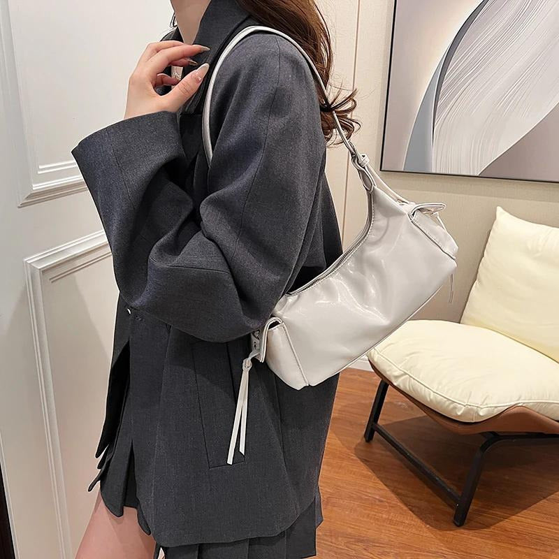 White glossy hobo shoulder bag with adjustable strap, side lace-up pockets, and sleek zip closure design