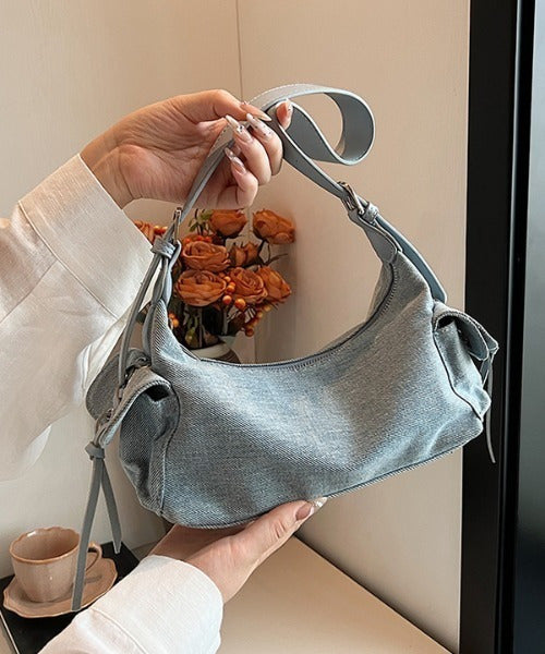 Blue glossy hobo shoulder bag with adjustable strap, side lace-up pockets, and sleek zip closure design