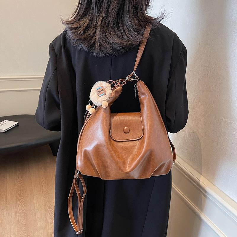 Coffee slouchy hobo shoulder bag in soft vegan leather with pom-pom keychain, versatile crossbody handbag for women