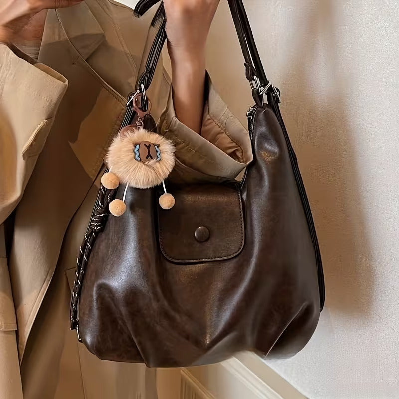 Brown slouchy hobo shoulder bag in soft vegan leather with pom-pom keychain, versatile crossbody handbag for women