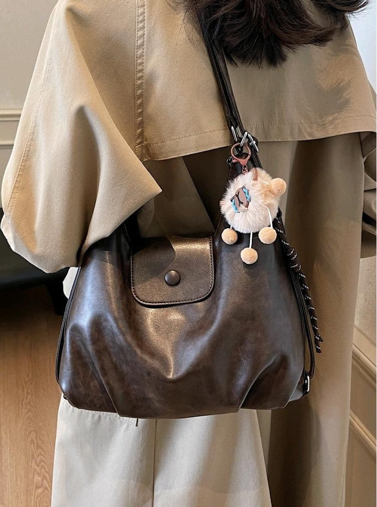 Brown slouchy hobo shoulder bag in soft vegan leather with pom-pom keychain, versatile crossbody handbag for women