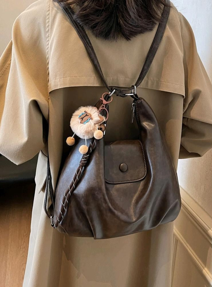 Brown slouchy hobo shoulder bag in soft vegan leather with pom-pom keychain, versatile crossbody handbag for women