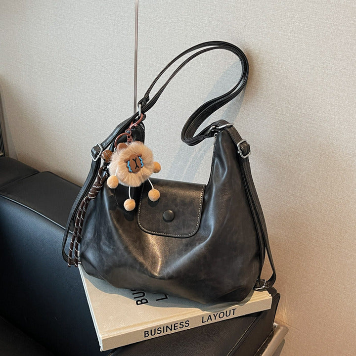 Black slouchy hobo shoulder bag in soft vegan leather with pom-pom keychain, versatile crossbody handbag for women