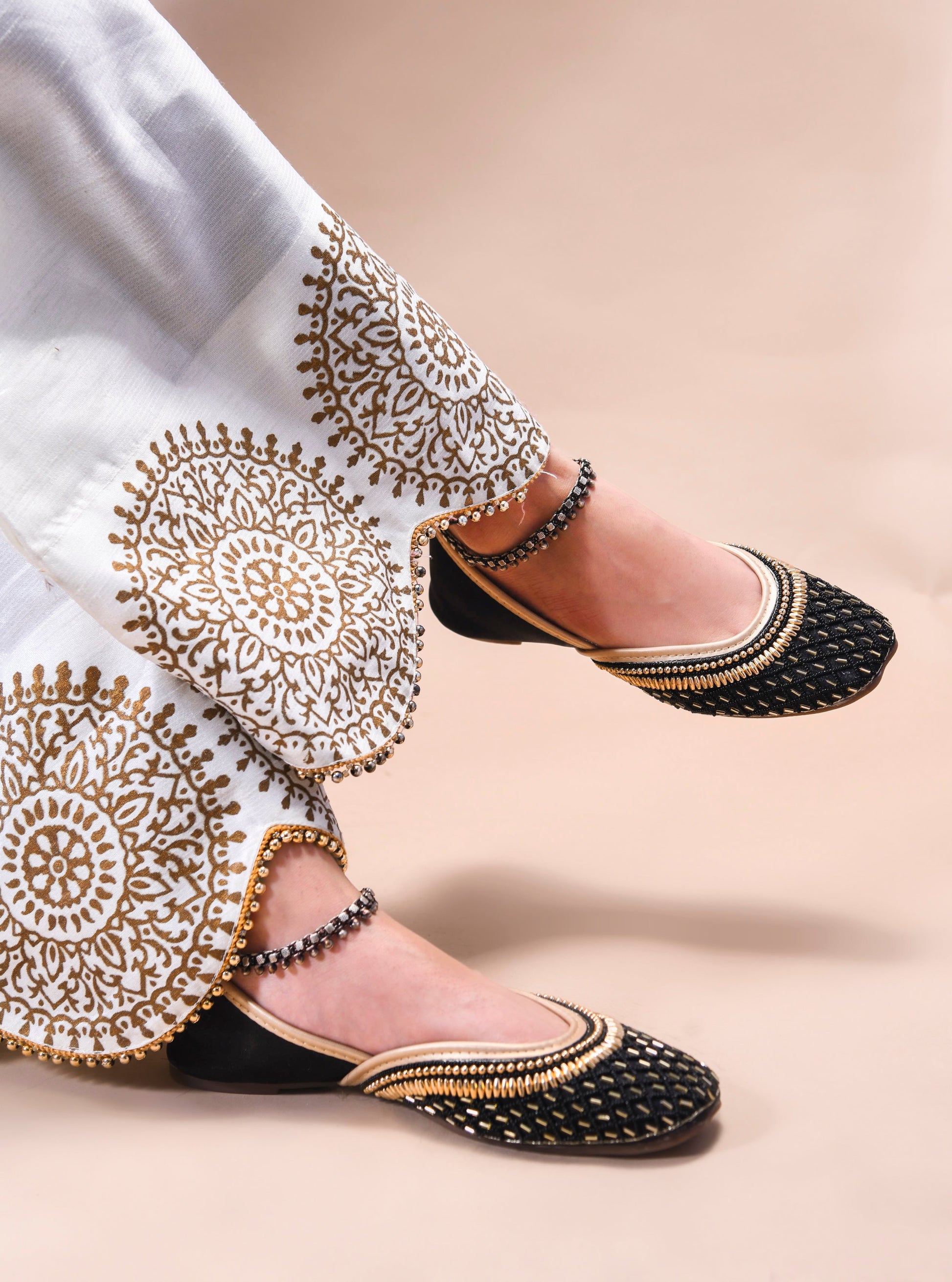 traditional juttis with intricate beaded work in a geometric pattern on the upper
 Black