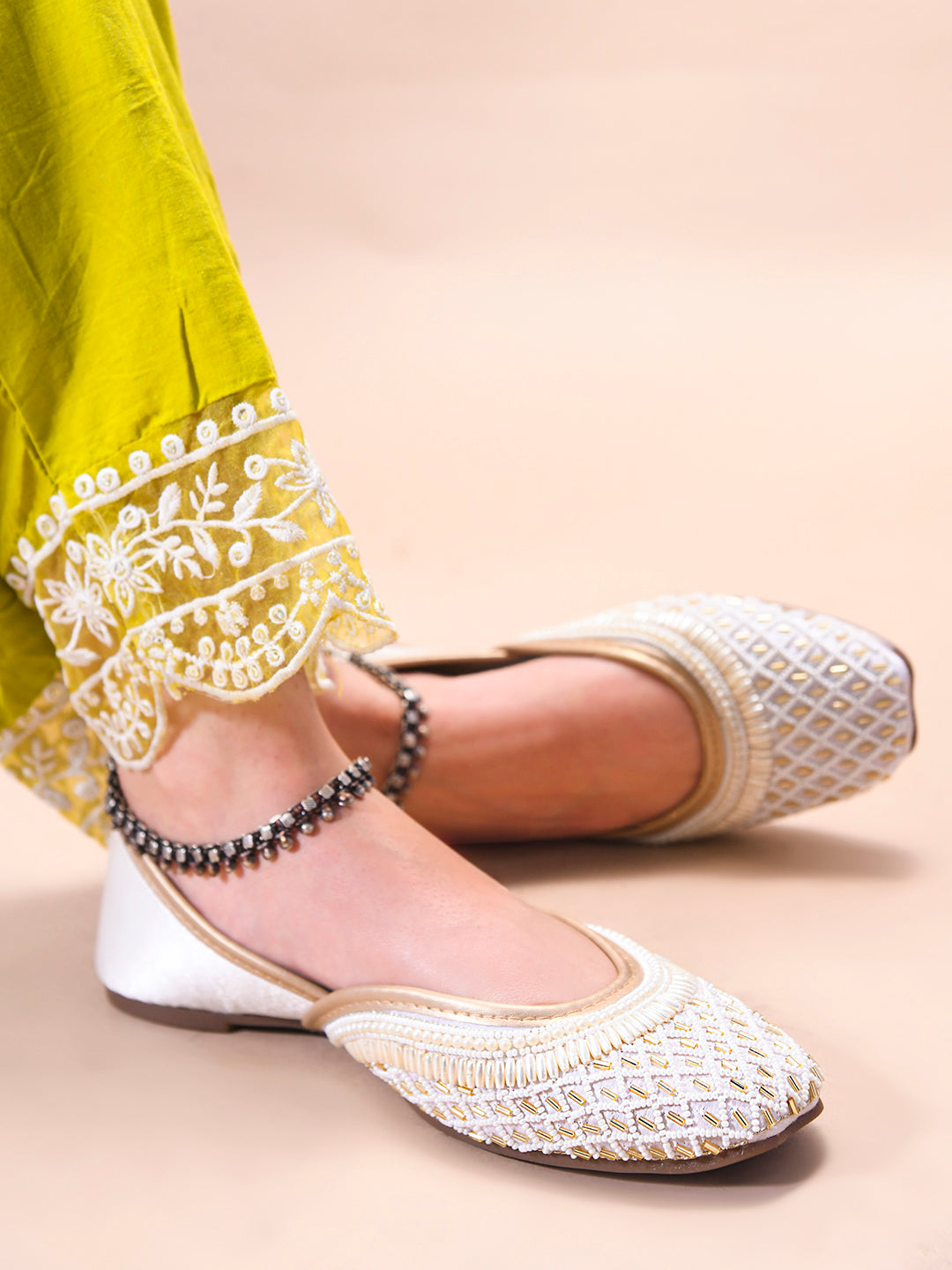 traditional juttis with intricate beaded work in a geometric pattern on the upper
 White