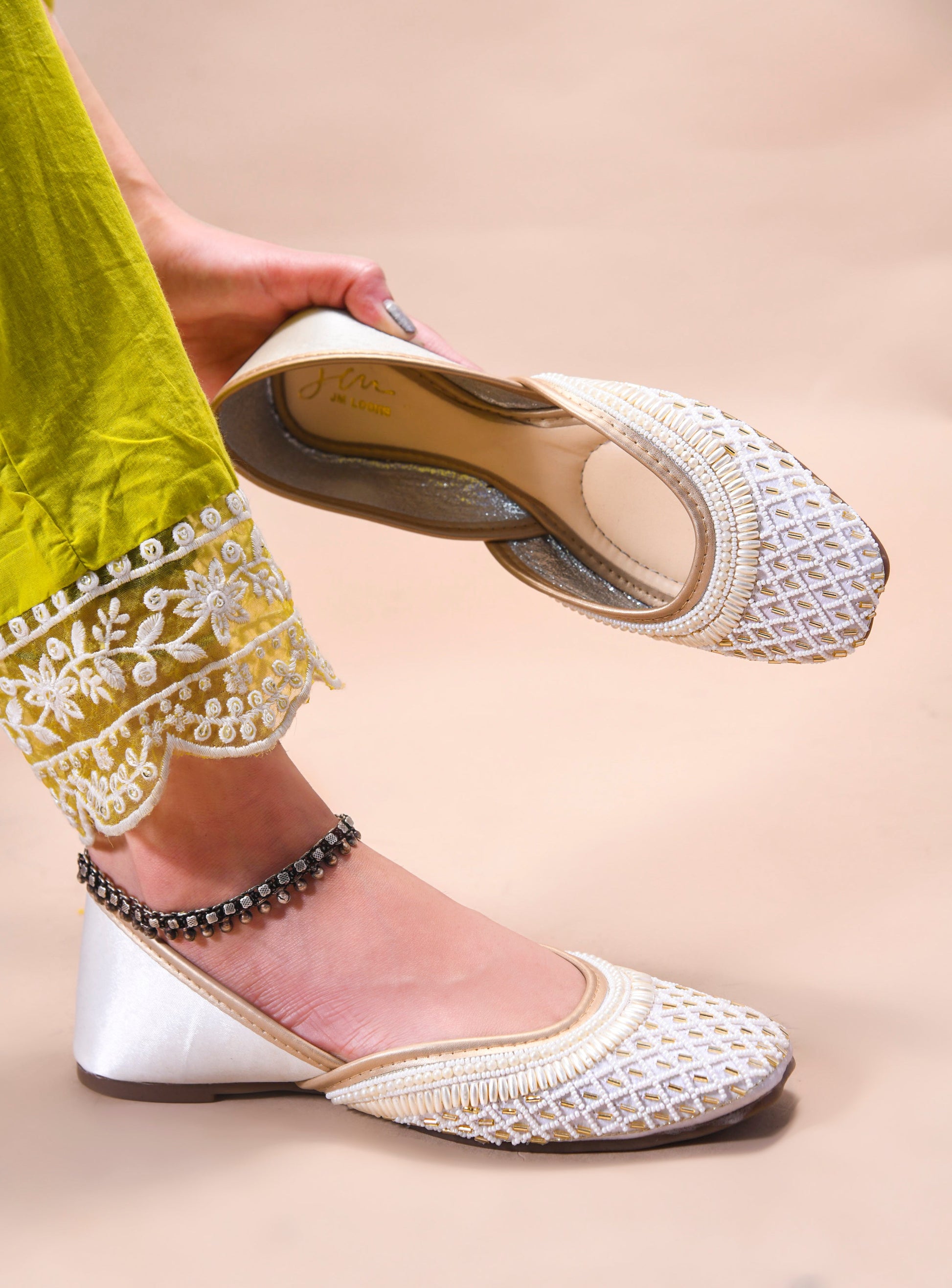 traditional juttis with intricate beaded work in a geometric pattern on the upper
 White