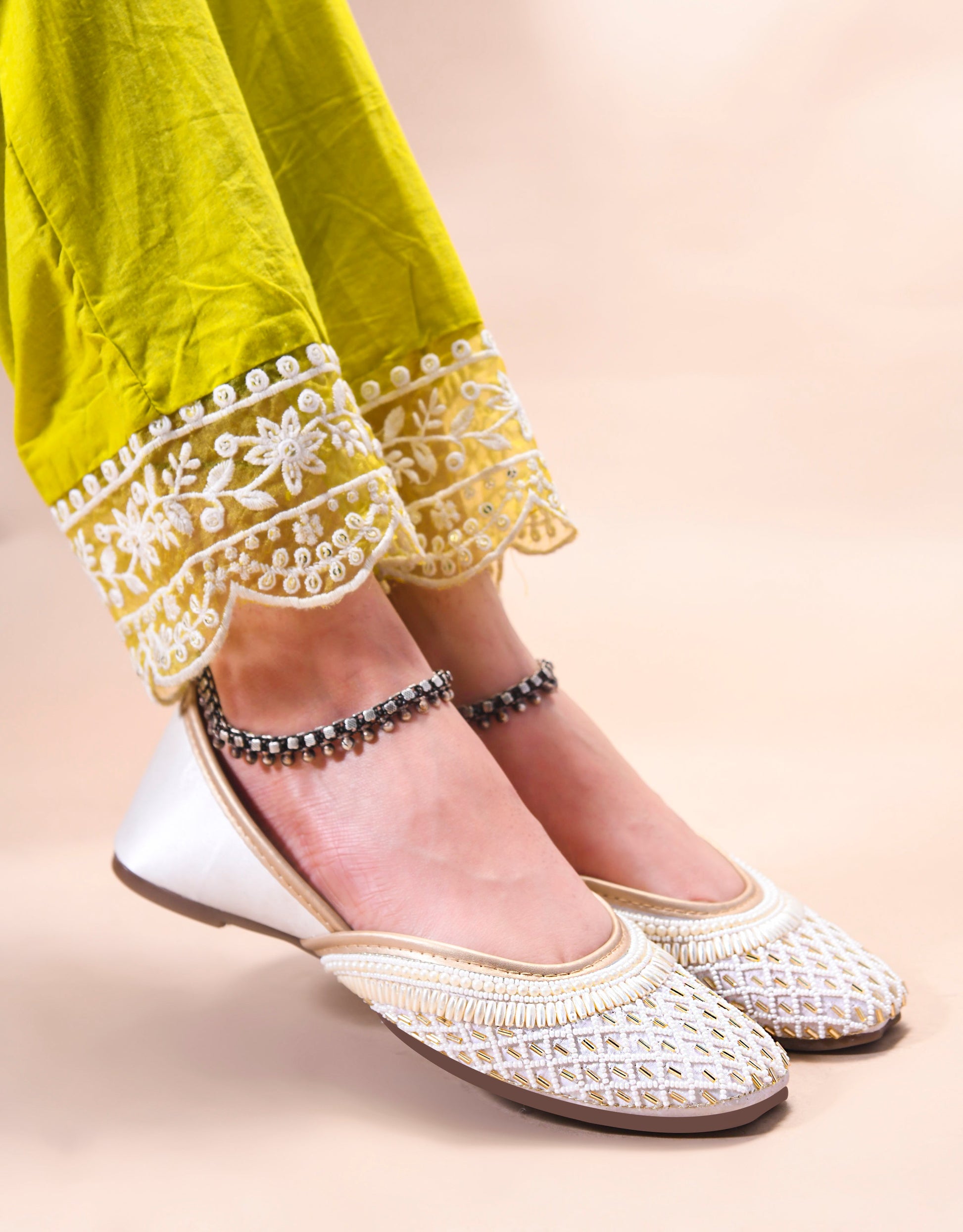 traditional juttis with intricate beaded work in a geometric pattern on the upper
 White