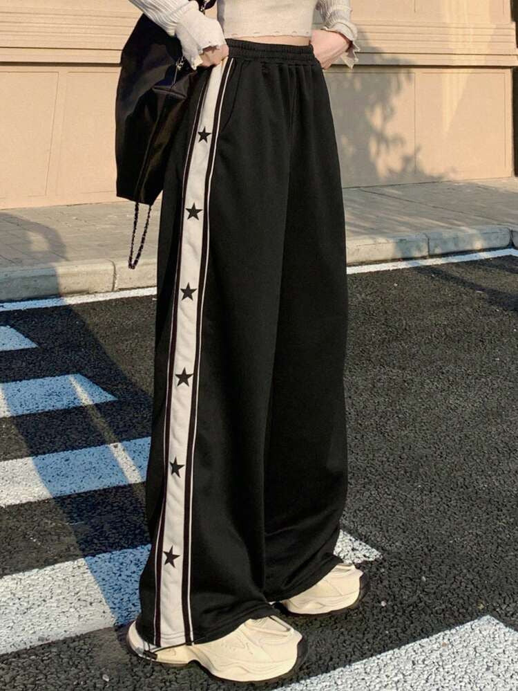 Wide leg track pants for women in black featuring white side stripe with black star print