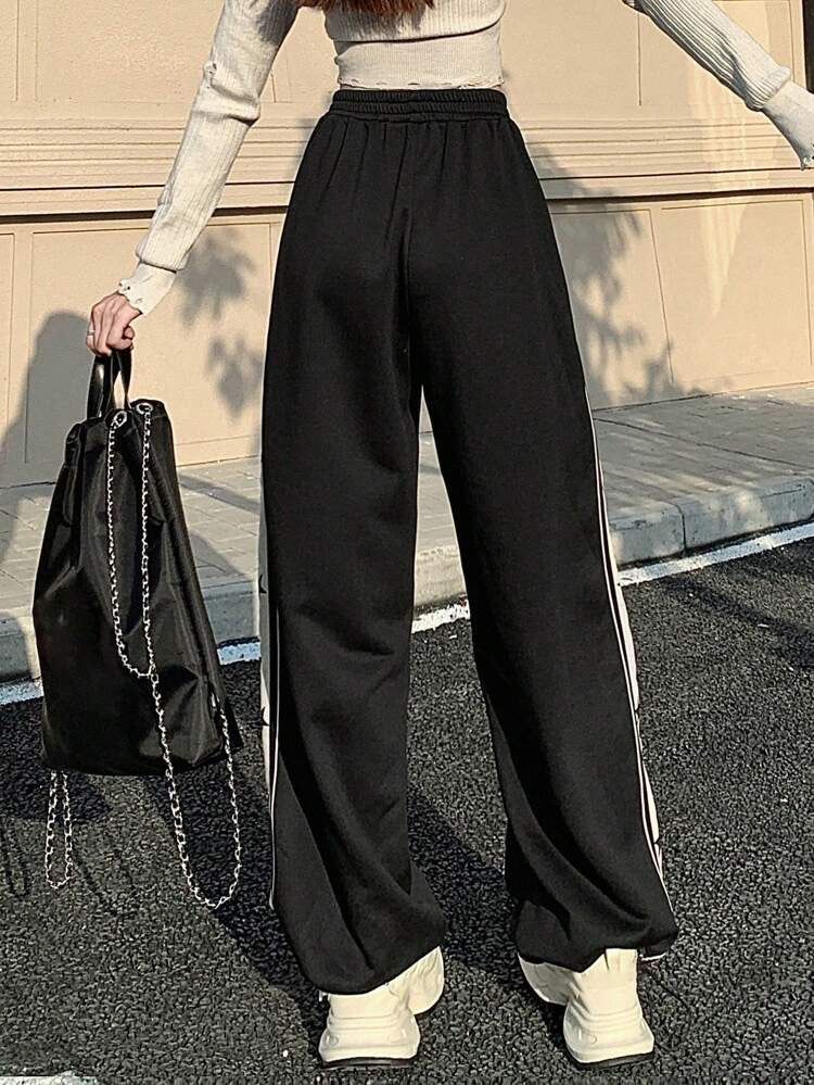 Wide leg track pants for women in black featuring white side stripe with black star print