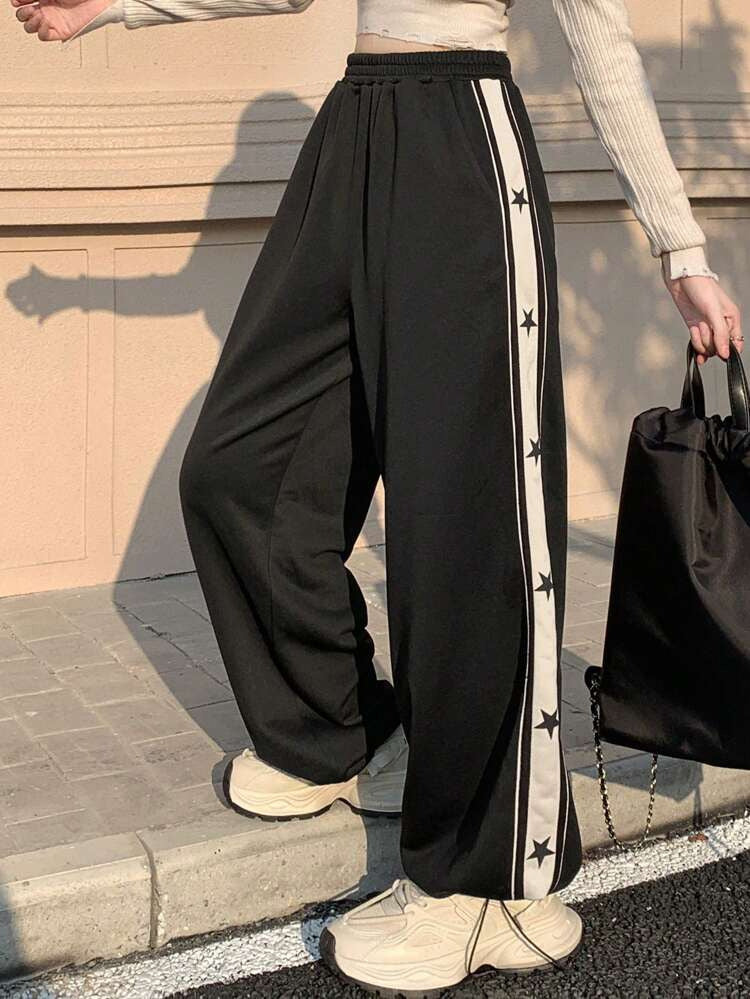 Wide leg track pants for women in black featuring white side stripe with black star print