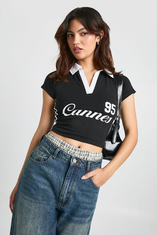 Black collared polo t-shirt for women featuring white contrast collar, side stripe, and printed graphic detailing