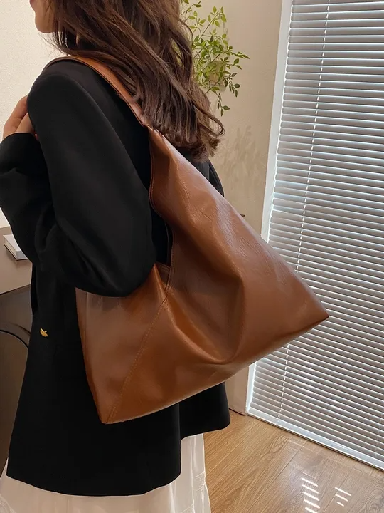 Tan vegan leather hobo tote bag with single shoulder strap, wrinkled texture, asymmetric zigzag silhouette.