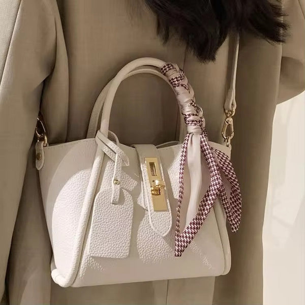 Cream structured handbag with houndstooth scarf tied handle, gold hardware, detachable crossbody strap, textured faux-leather design.