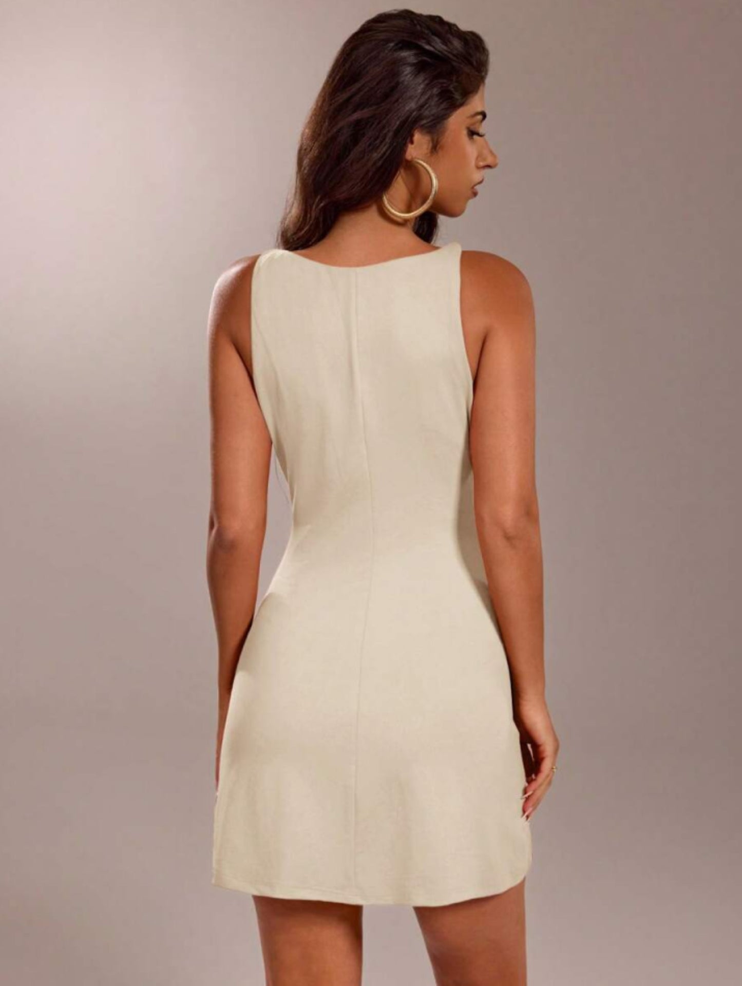 Apricot bodycon mini dress with high boat neckline and sleeveless fit, styled with gold hoop earrings