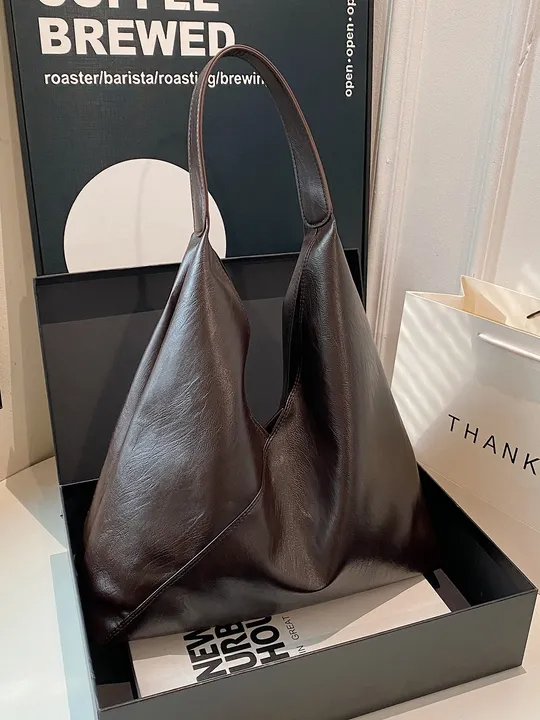 Brown vegan leather hobo tote bag with single shoulder strap, wrinkled texture, asymmetric zigzag silhouette.