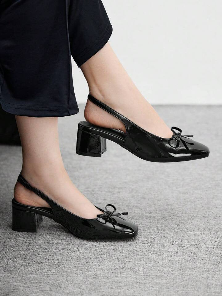 Women's black patent Mary Jane slingback block heels with bow detail, square toe and chunky heel.